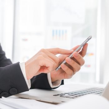 Closeup of business woman hand typing on laptop keyboard with  mobile phone